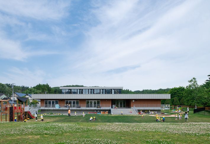 一面に緑が広がる園庭では、緑豊かな木々と景観になじむ園舎を背景に子どもたちが遊びまわっています。