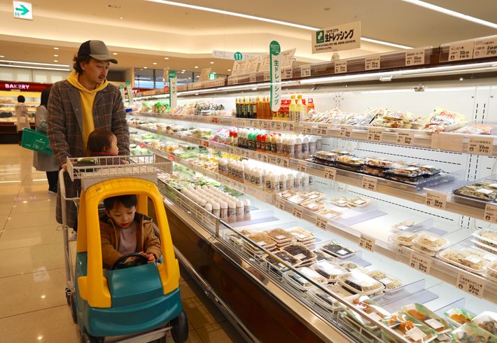 子どもと一緒にスーパーマーケット内で買い物をする写真。子どもは楽しそうに自動車タイプのショッピングカートを運転しています。