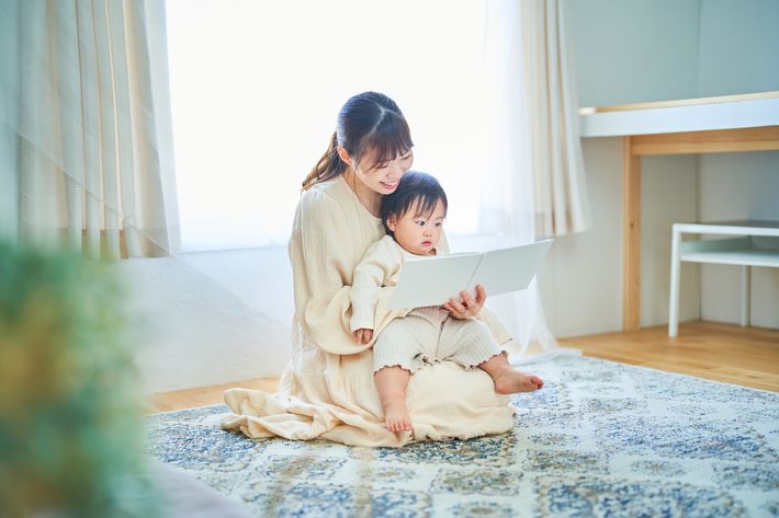 母親が膝の上に小さな子どもを乗せて読み聞かせをする様子