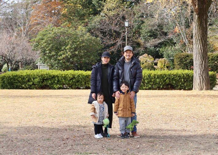 広々とした公園内の木々を背景に、保育園留学を利用した筆者の家族4人が笑顔で並ぶ写真。