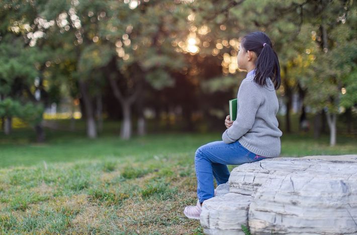 本を抱えてひとりで座っている女の子